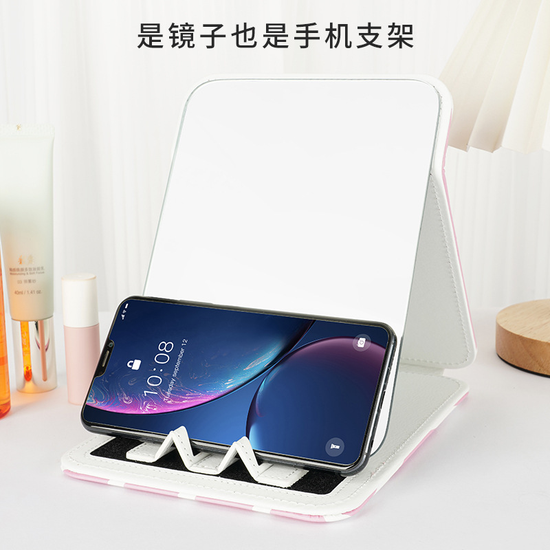Một chiếc gương nhỏ trên điện thoại di động mang một cái bàn với một bộ sưu tập mỹ phẩm của sinh viên.