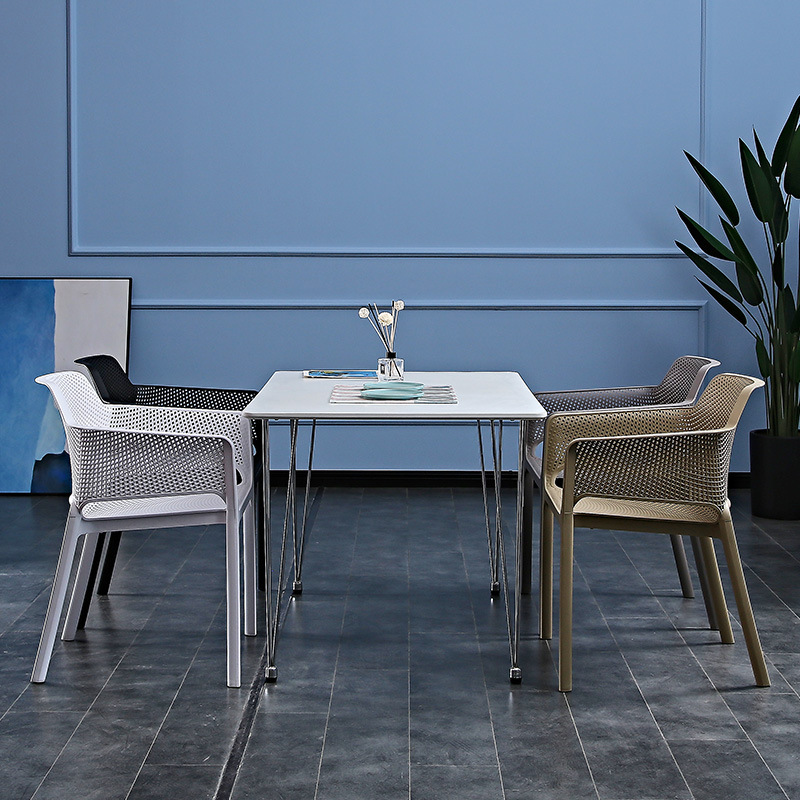 A plastic chair home with a thicker arm by a back bench and a table and chair in an outdoor courtyard.