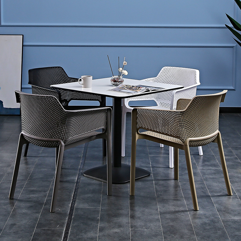 A plastic chair home with a thicker arm by a back bench and a table and chair in an outdoor courtyard.