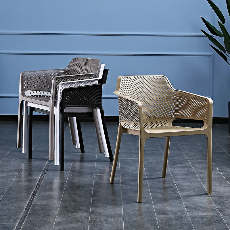 A plastic chair home with a thicker arm by a back bench and a table and chair in an outdoor courtyard.