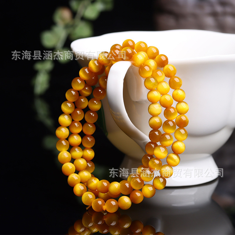 Wholesale of natural crystal tiger eyestones, rounded with golden-coloured cat-eyes.