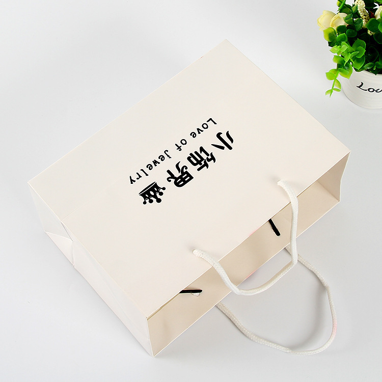 Hand-in-hand white card paper bag at the fashion shop to customize the shopping bag for creative gift bags