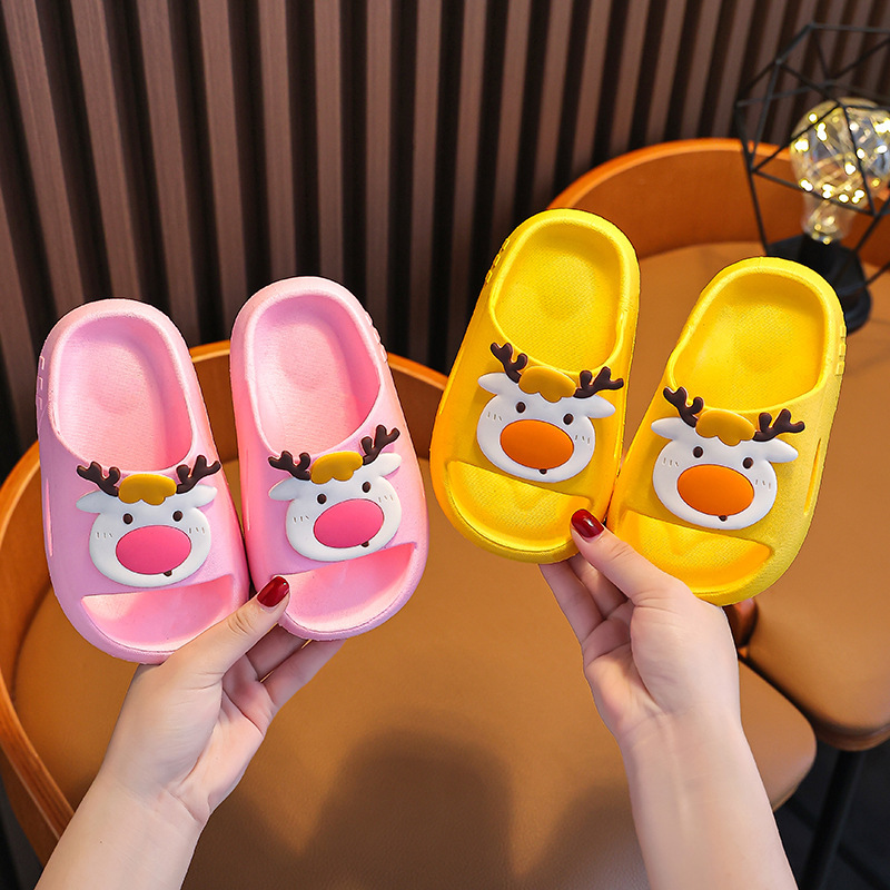 Những cô gái mang giày dép trẻ em mang những đôi dép mới của nai hoạt hình Giáng sinh dưới đáy bồn tắm.