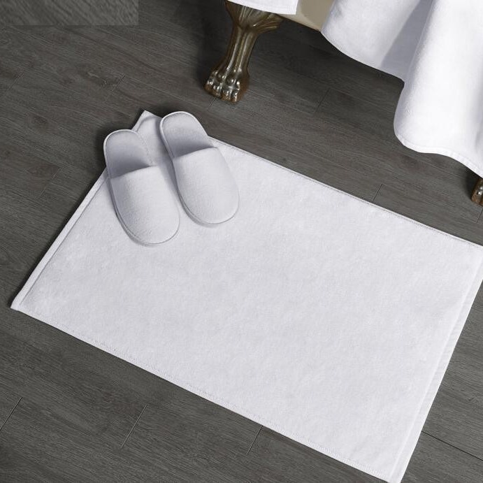 Five star-class net cotton hotel towels in the bathroom with all-comfort pads on the floor.